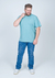 Camiseta Plus Size Malha Relevo na cor azul claro, usada por um homem com jeans e tênis branco, em fundo neutro.
