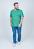 Camiseta plus size básica lisa na cor verde, feita de 100% algodão, modelada por um homem que caminha.