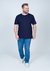 Camiseta básica plus size azul marinho em algodão, modelo masculino, com calça jeans e tênis branco, posando de frente.