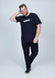 Camiseta plus size preta com estampa na parte frontal, modelo masculino posando de forma descontraída.