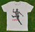 Camiseta areia/cru com estampa de Eusébio, o famoso jogador moçambicano conhecido como a Pantera Negra, em ação.
