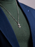 Corrente de prata 925 da marca Morelli Joias, com acabamento em ródio e pingente em forma de âncora, usada sobre camiseta verde e blazer azul