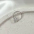 Piercing cravejado em zircônia com formato quadrado, em fundo claro e liso.
