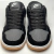 Vista superior dos tênis Nike Dunk Low, modelo feminino, na cor cinza e preto, com acabamento em camurça e detalhes em couro.