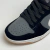 Tênis Nike Dunk Low feminino, com cabedal cinza e preto, feito em material sintético e camurça, destacado na parte superior da imagem.