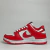 Tênis feminino Nike Dunk Low vermelho e branco, feito de material sintético, posicionado lateralmente.