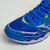 Tênis Mizuno Wave Creation 20 na cor grafite e vermelho com detalhes em azul e verde, focando na parte superior e na malha respirável do calçado.