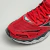 Tênis Mizuno Wave Creation 20 na cor vermelha e detalhes em grafite e laranja, destacando o design de malha e cadarços.