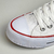 Tênis All Star Cano Baixo Branco com detalhes em vermelho, mostrando a parte frontal e lateral do calçado.