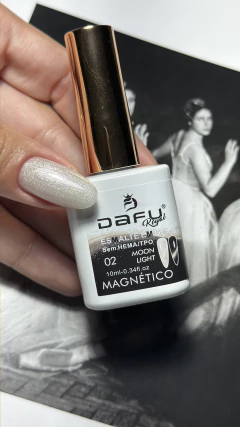 Unha com esmalte em gel magnético branco perolado da marca Dafu Royal, modelo Moon Light, sendo segurado por uma mão com unha decorada no mesmo esmalte