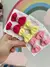 Conjunto de laços gravatinhas coloridos com pérolas, apresentados em um cartão. As cores incluem rosa, amarelo e vermelho.