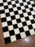 Alfombra Damero con diseño de cuadros en blanco y negro sobre un suelo de madera