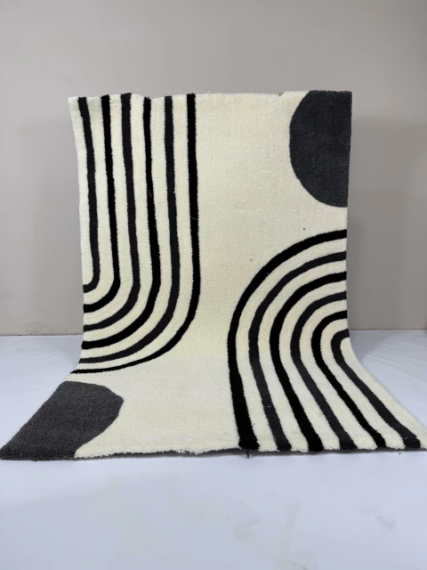 Alfombra de jardín con diseño en blanco y negro, mostrando patrones de líneas y círculos.