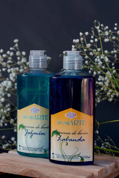Botellas de espumas de baño aromARTE aromáticas de jazmín y lavanda sobre una superficie de madera, decoradas con flores blancas.