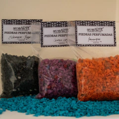 Piedras perfumadas en tres colores: negro, morado y naranja, con etiquetas que indican sus fragancias.