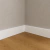 Rodapé de poliestireno branco liso de 20 cm instalado em canto de ambiente, com piso de madeira e parede bege, ideal para decoração de interiores.