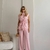 Mulher vestindo conjunto feminino de parka rosa sem mangas e calça pantalona rosa, posando em ambiente minimalista.