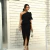 Mulher usando conjunto feminino com blusa de um ombro só e saia midi preta, look elegante e moderno.