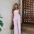 Mulher vestindo conjunto assimétrico rosa com blusa regata e calça pantalona, ideal para moda feminina moderna.