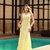 Mulher vestindo vestido amarelo longo Meire ao lado de uma piscina, em ambiente sofisticado e urbano.