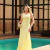 Mulher vestindo vestido amarelo longo Meire ao lado de uma piscina, em ambiente sofisticado e urbano.