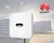 Inversor solar Huawei blanco con paneles solares al fondo y logo de Huawei