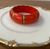 Pulseira em madeira na cor vermelha com detalhes no dourado. (um detalhe)