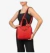Cartera roja RAFITTHY sostenida por una mujer que viste un atuendo negro.