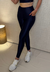 Legging Elite Wear de cor azul marinho, com ajuste perfeito e bolso lateral, usada por uma modelo em ambiente interno.
