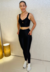 Modelo vestindo conjunto fitness preto, composto por top e legging, exibindo conforto e estilo.