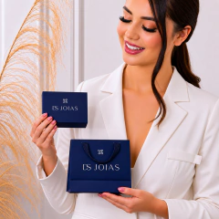 Mulher sorridente segurando caixa e sacola azul com logo DS Joias, vestindo blazer branco