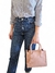 Uma mulher segurando uma bolsa feminina tiracolo média rosa, com uma camisa listrada e jeans.