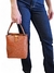 Mulher segurando uma bolsa tiracolo preta com textura de croco, enquanto veste calças jeans.