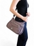 Bolsa feminina transversal média em cor roxa, sendo segurada por uma mulher, com alça longa e detalhes em zíper.