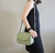 Mulher usando uma bolsa feminina transversal baú média verde menta em couro legítimo.