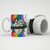 Caneca branca com design colorido da linha Pride, apresentando um coração e a frase "Ame quem você quiser".