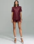 Mulher vestindo camisa oversize verde marsala Noir de manga curta, com botões frontais e bolsos, combinada com shorts da mesma cor.