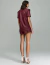 Mulher vestindo camisa oversize na cor marsala da marca Verde Marsala Noir, vista de costas, combinada com salto alto branco.