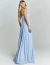 Mulher vestindo vestido de festa longo azul claro com decote transado, modelo San Carlos, em tecido plissado elegante.