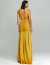 Mulher vestindo um vestido de festa longo amarelo com drapeado na cintura, visto de costas.