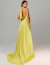 Mulher vestindo vestido de festa longo de cetim amarelo com decote nas costas e amarração no pescoço, ideal para eventos sofisticados.