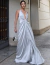 Vestido de festa longo de cetim prata sendo usado por uma mulher em um ambiente urbano elegante ideal para convidada de formatura
