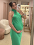 Mulher usando vestido de festa longo verde bandeira com decote americano, tirando selfie em um espelho.
