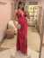 Mulher usando vestido de festa longo de cetim magenta com decote profundo e fenda lateral, segurando uma clutch prateada.
