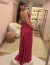 Mulher vestindo um vestido de festa longo de cetim magenta em um ambiente elegante.