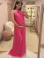 Mulher vestindo um vestido de festa longo de cetim pink, posando em frente ao espelho.