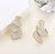 Aretes Dorados con Diseño Orgánico y Esmaltado Blanco