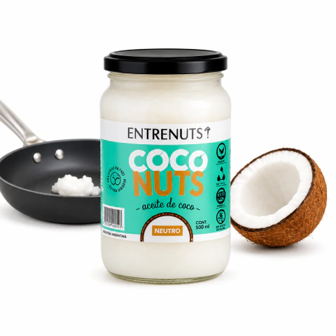 Frasco de aceite de coco neutro Entrenuts de 500 ml junto a una sartén con aceite y un coco partido a la mitad