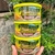 Três potes de Bananada Cremosa da marca Serra Verde, com destaque para o rótulo e bananas ao fundo.
