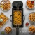 Freidora eléctrica de aceite SUONO de 3 litros con visor de vidrio, en uso friendo aros de cebolla, rodeada de platos con papas fritas, mariscos y bocadillos en una mesa de cocina.